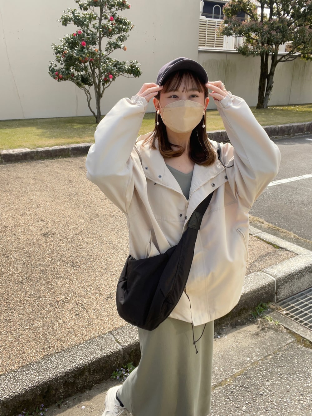 ホワイト系のマウンテンパーカー、グリーン系のワンピース/ドレス、ホワイト系のスニーカーを着用したレディースの春コーディネートの2枚目の写真