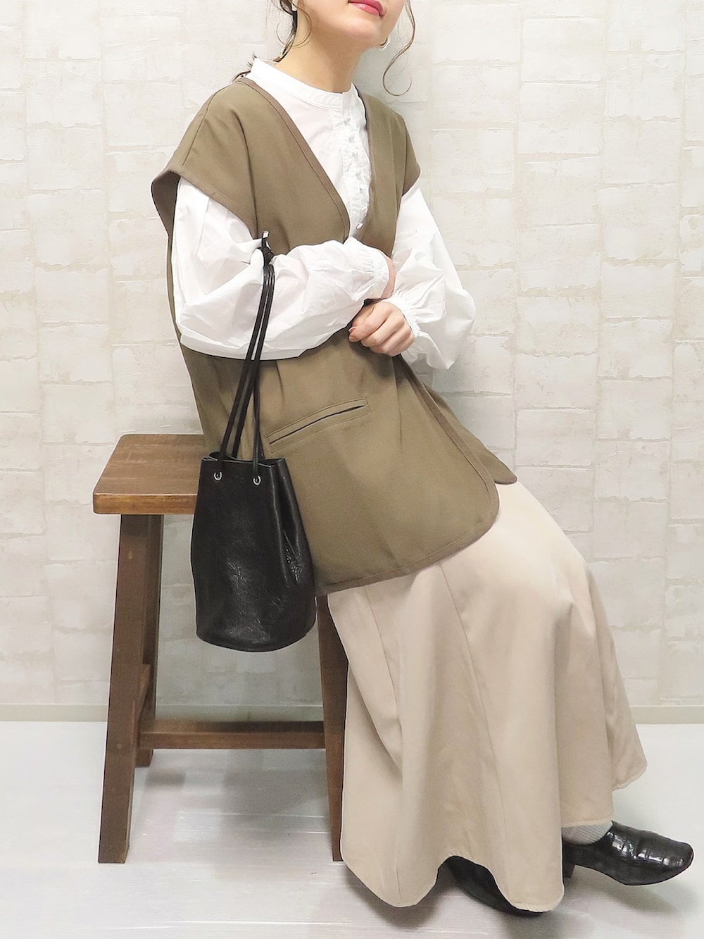 ホワイト系のシャツ/ブラウス、ブラウン系のベスト、ベージュ系のスカートを着用したレディースの冬コーディネートの4枚目の写真