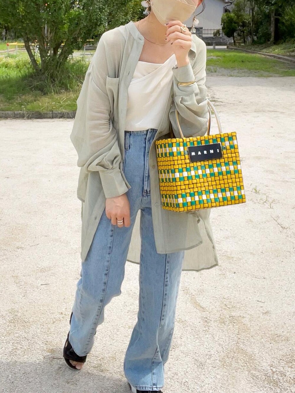 グリーン系のシャツ/ブラウス、ホワイト系のキャミソール、ブルー系のデニムパンツを着用したレディースの夏コーディネートの5枚目の写真