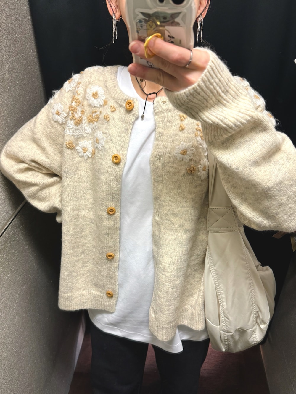 ベージュ系のニット/セーター、ホワイト系のショルダーバッグ、ブラック系のデニムパンツを着用したレディースの秋コーディネートの4枚目の写真