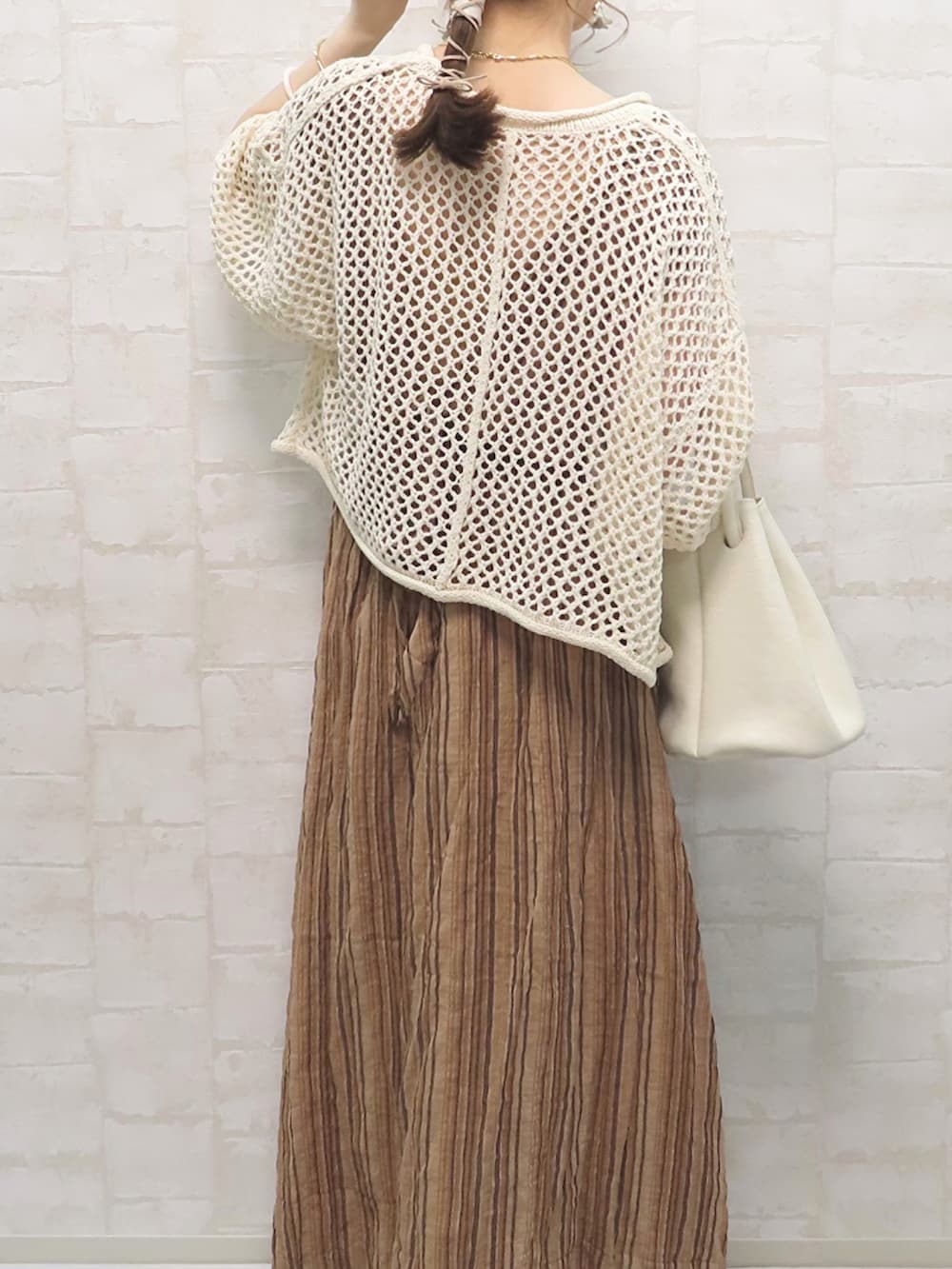 ブラウン系のワンピース、ホワイト系のニット/セーター、ホワイト系のハンドバッグを着用したレディースの春コーディネートの3枚目の写真