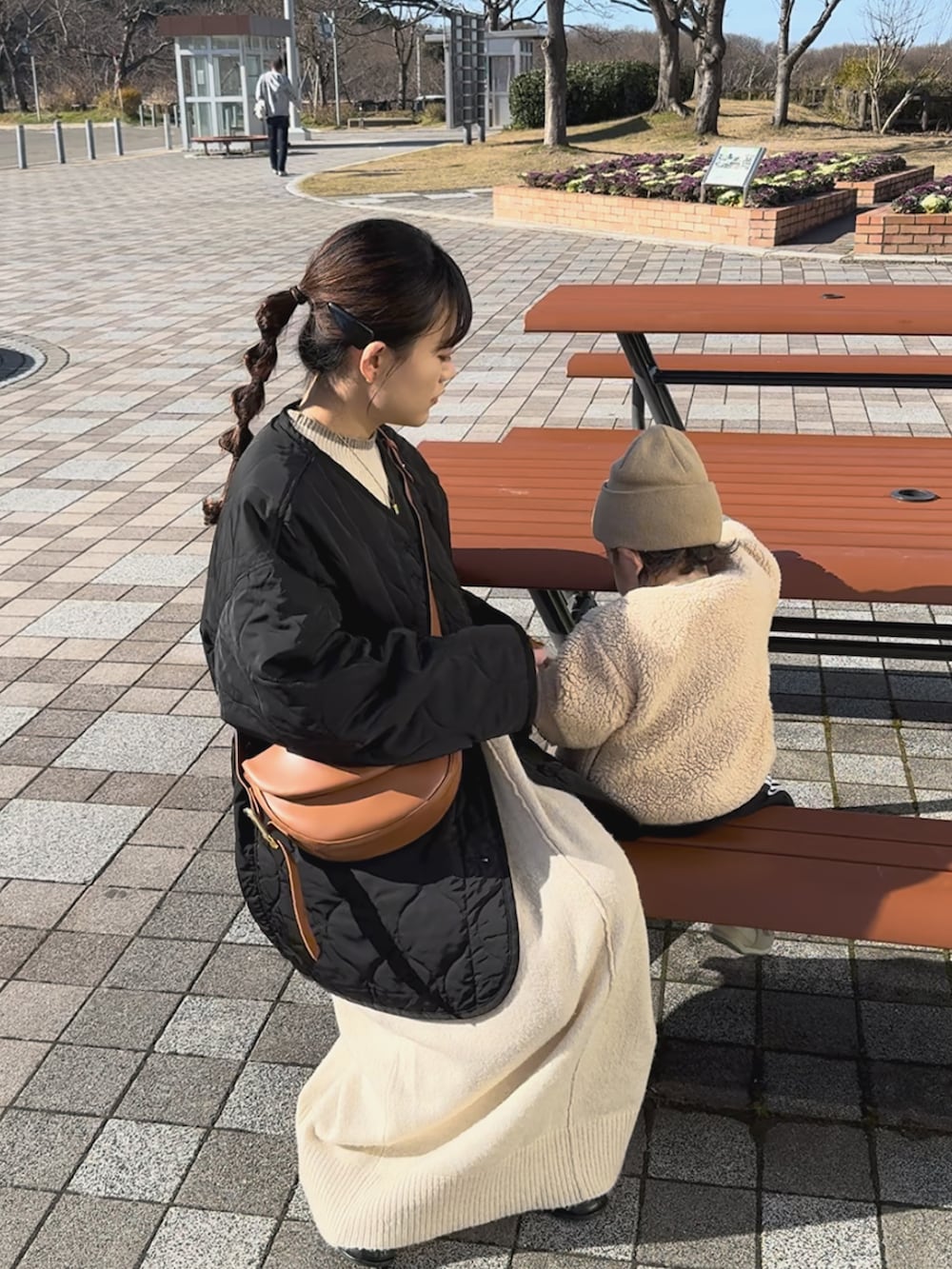 ブラック系のノーカラージャケット、ホワイト系のワンピース、ブラウン系のハンドバッグを着用したレディースの冬コーディネートの2枚目の写真