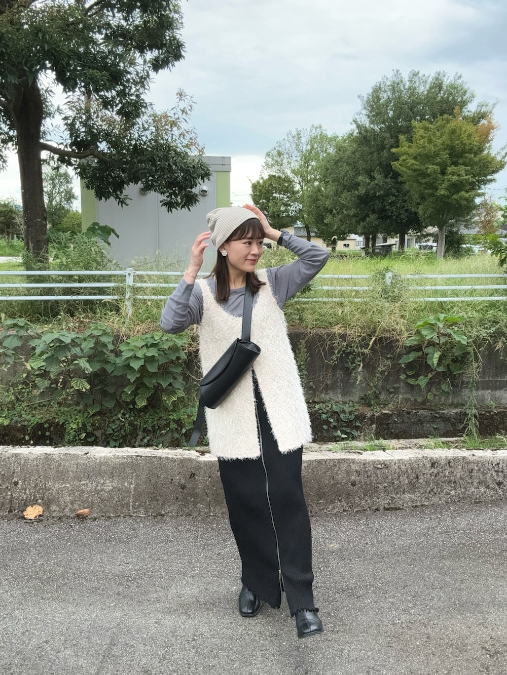 グレー系のTシャツ/カットソー、ホワイト系のベスト、ブラック系のスカートを着用したレディースの秋コーディネートの4枚目の写真