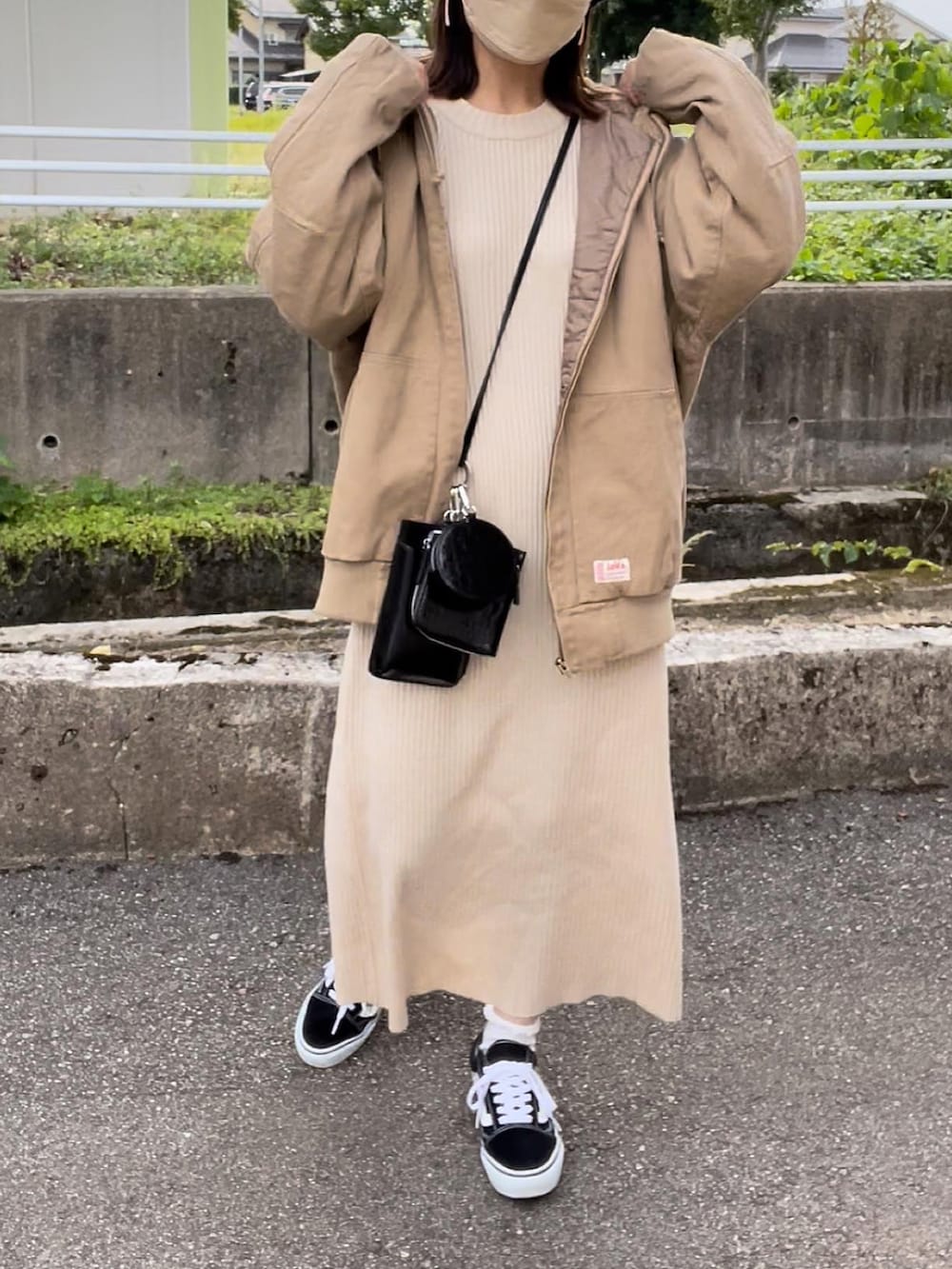 ベージュ系のブルゾン、ホワイト系のワンピース、ブラック系のショルダーバッグを着用したレディースの秋コーディネートの3枚目の写真