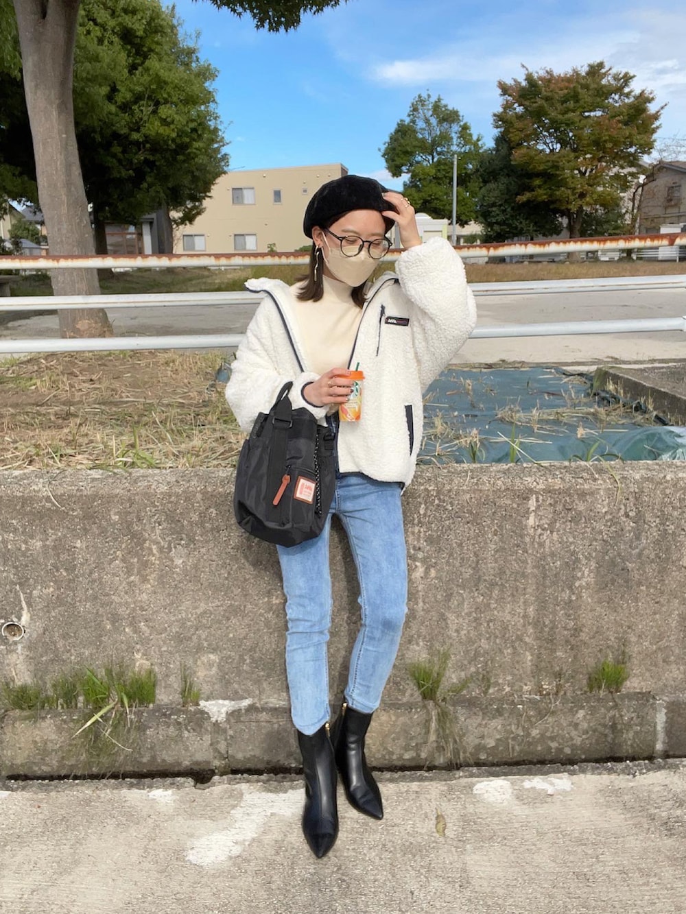 ホワイト系のブルゾン、ホワイト系のニット/セーター、ブラック系のショルダーバッグを着用したレディースの冬コーディネートの2枚目の写真