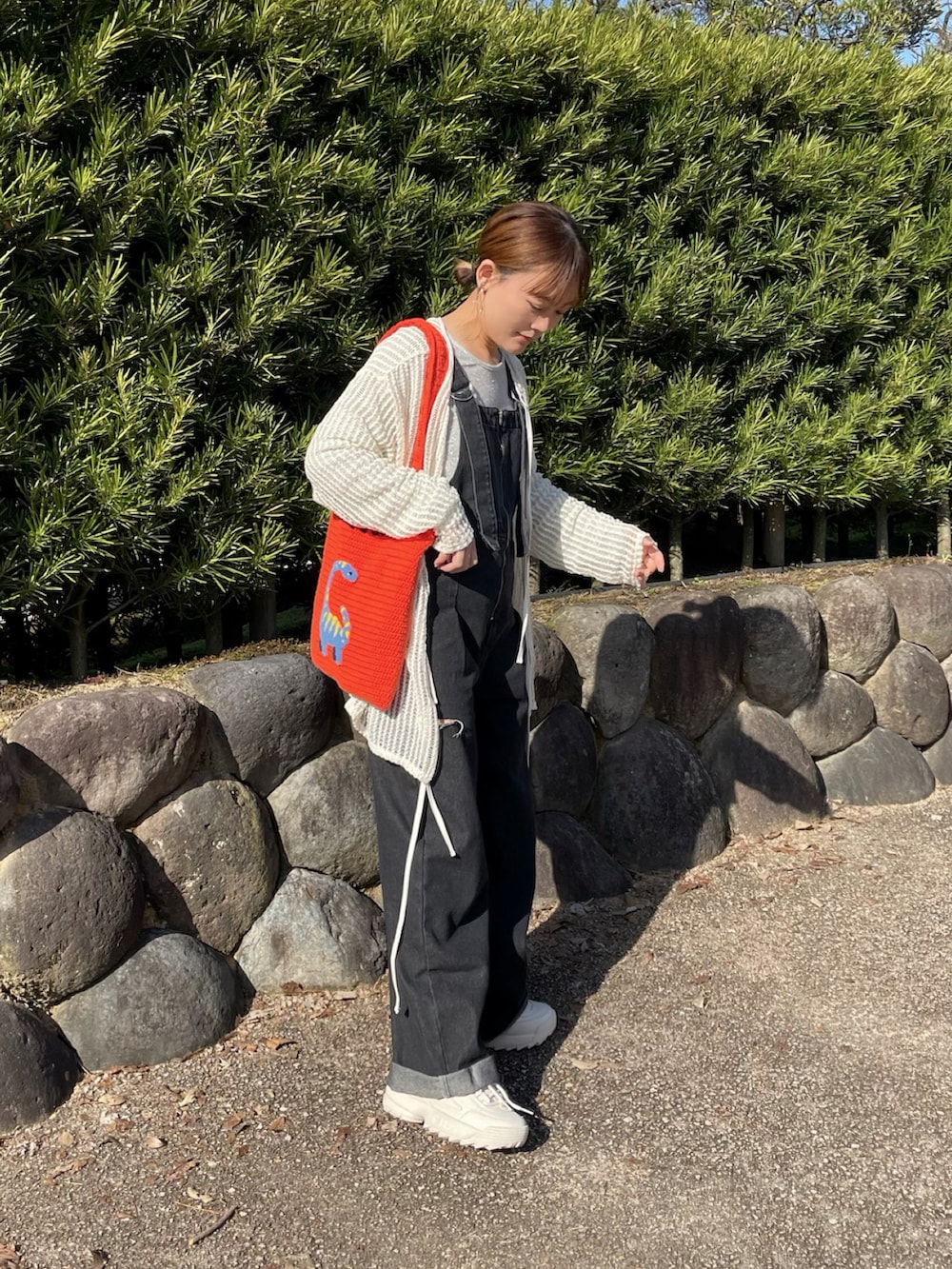 オレンジ系のトートバッグ、シルバー系のトップス、ホワイト系のカーディガン/ボレロを着用したレディースの春コーディネートの5枚目の写真