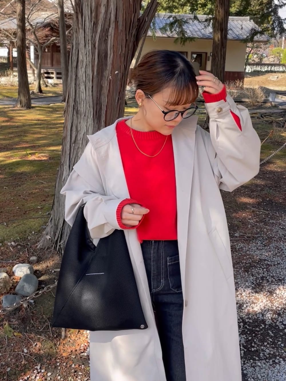 ベージュ系のトレンチコート、レッド系のニット/セーター、ブラック系のデニムパンツを着用したレディースの春コーディネートの3枚目の写真