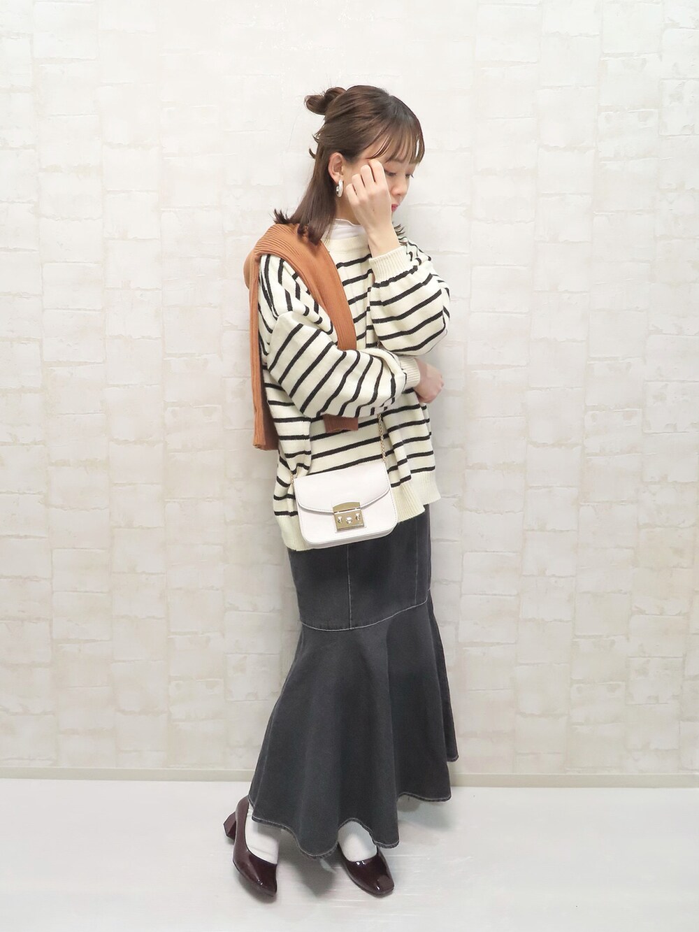 ホワイト系のニット/セーター、オレンジ系のニット/セーター、ブラック系のデニムスカートを着用したレディースの冬コーディネートの4枚目の写真