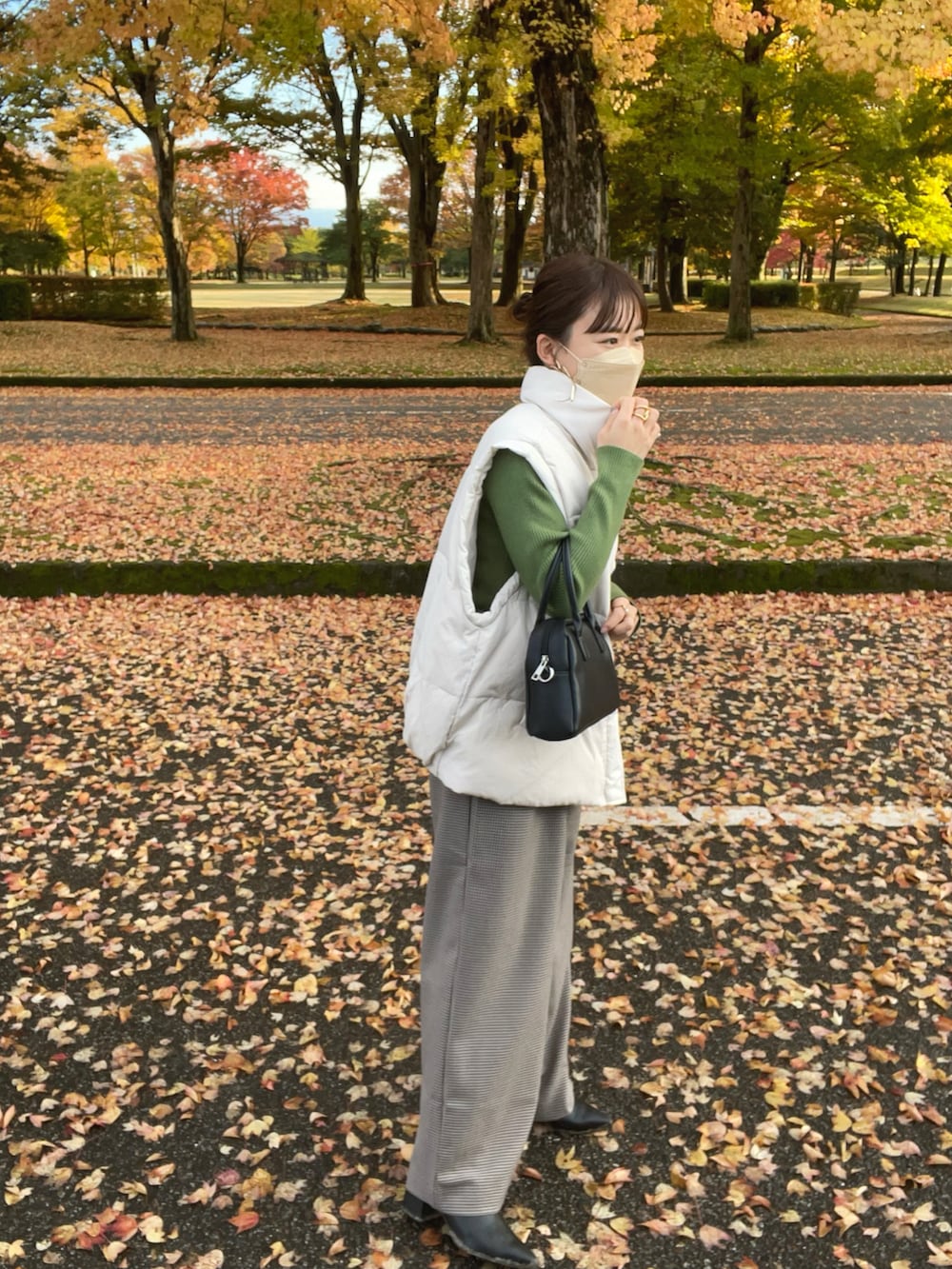 ベージュ系のその他パンツ、ホワイト系のダウンベスト、グリーン系のニット/セーターを着用したレディースの秋コーディネートの4枚目の写真