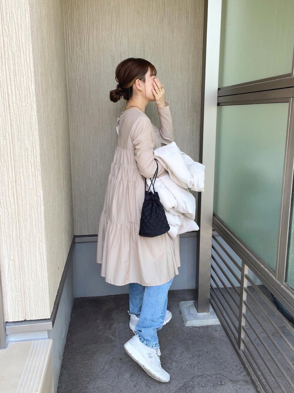 ベージュ系のワンピース、ホワイト系のダウンベスト、ブルー系のデニムパンツを着用したレディースの秋コーディネートの4枚目の写真