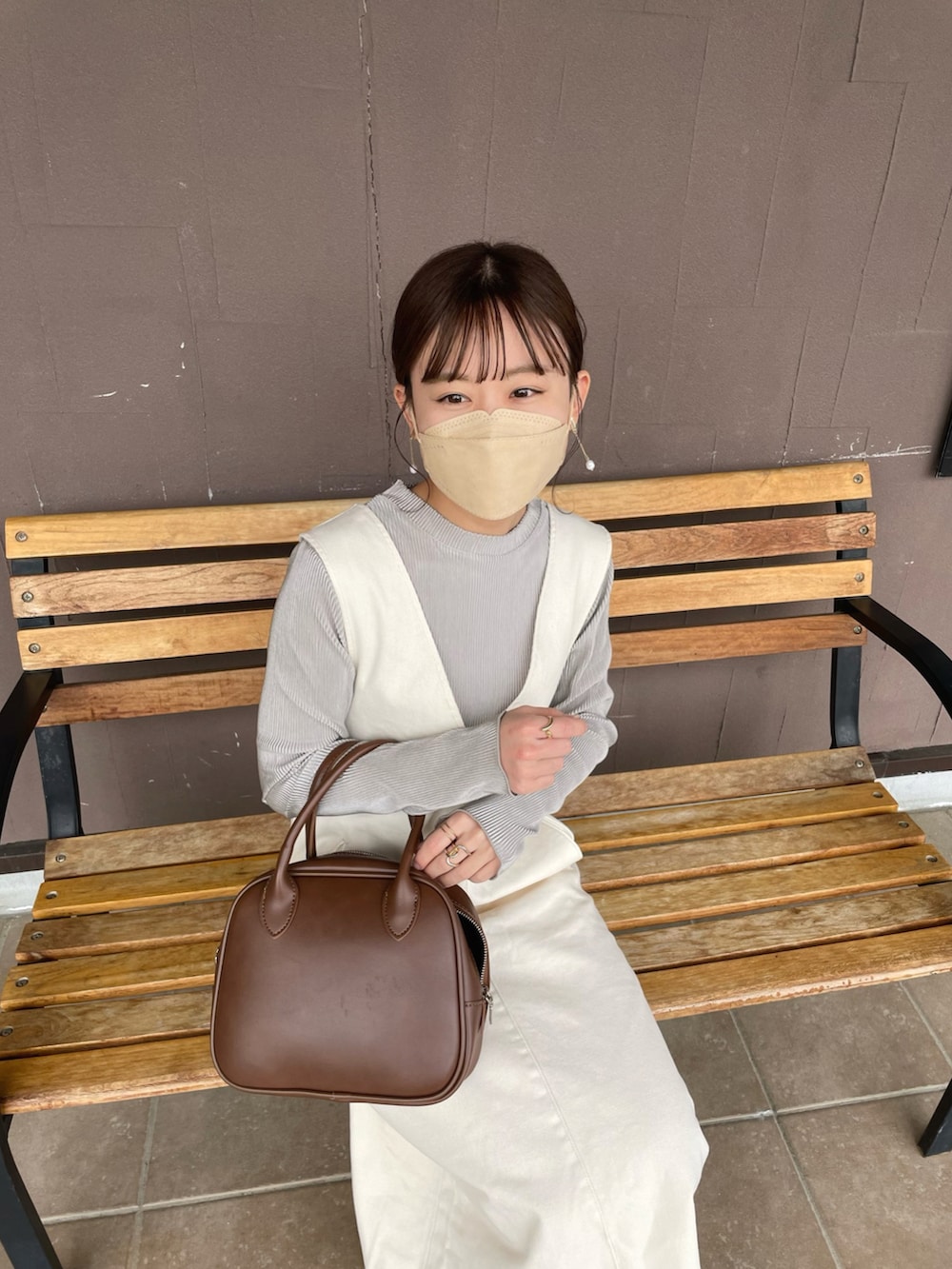 ベージュ系のTシャツ/カットソー、ホワイト系のジャンパースカート、ブラウン系のショルダーバッグを着用したレディースの春コーディネートの2枚目の写真