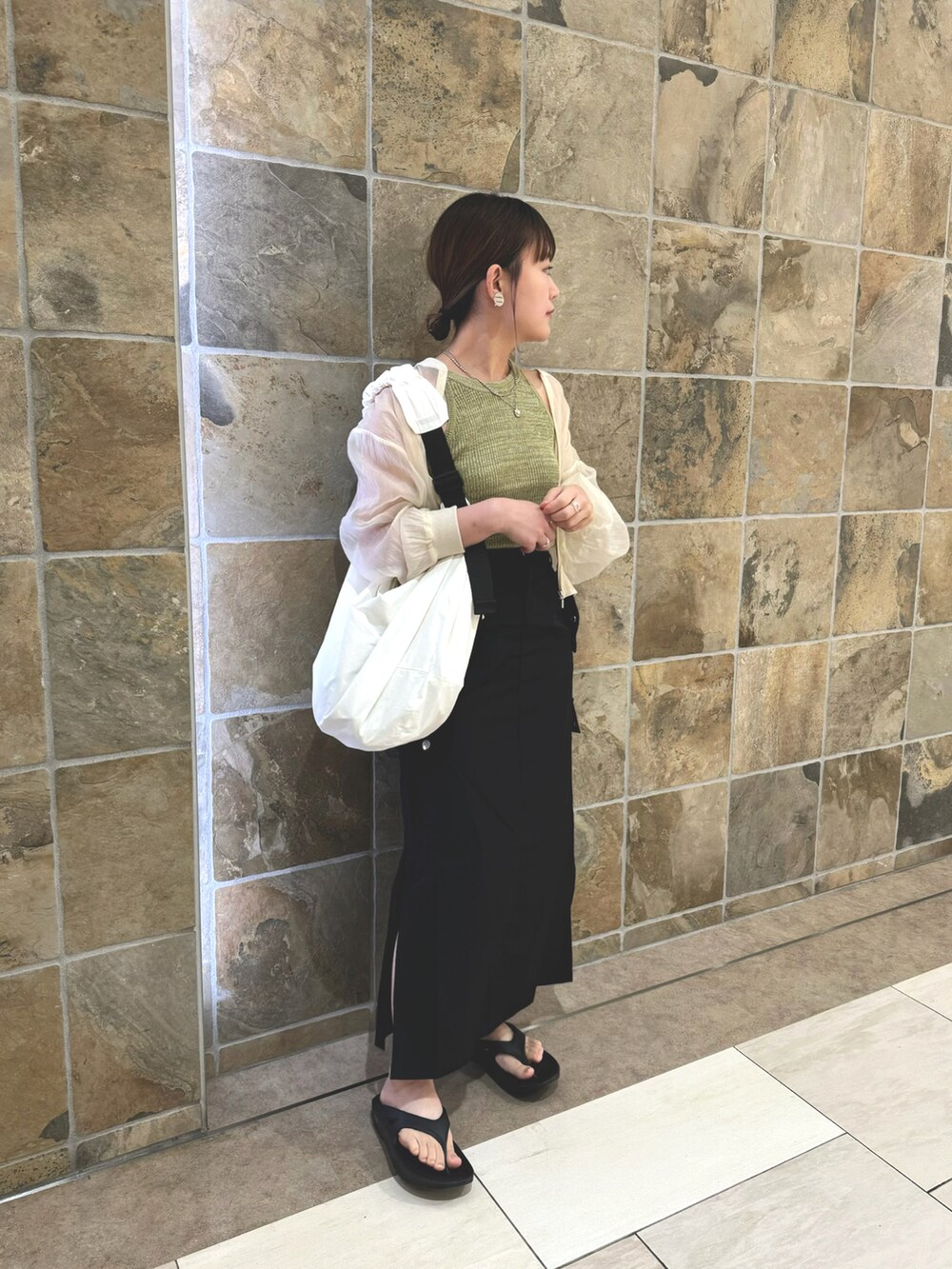 グリーン系のタンクトップ、ブラック系のスカート、ホワイト系のショルダーバッグを着用したレディースの夏コーディネートの3枚目の写真