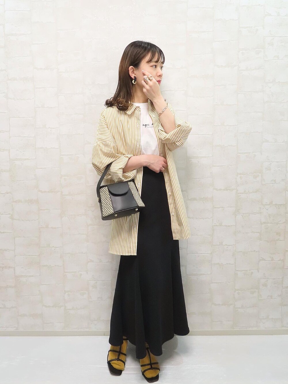 ブラック系のサンダル、イエロー系のシャツ/ブラウス、ホワイト系のTシャツ/カットソーを着用したレディースの春コーディネートの2枚目の写真