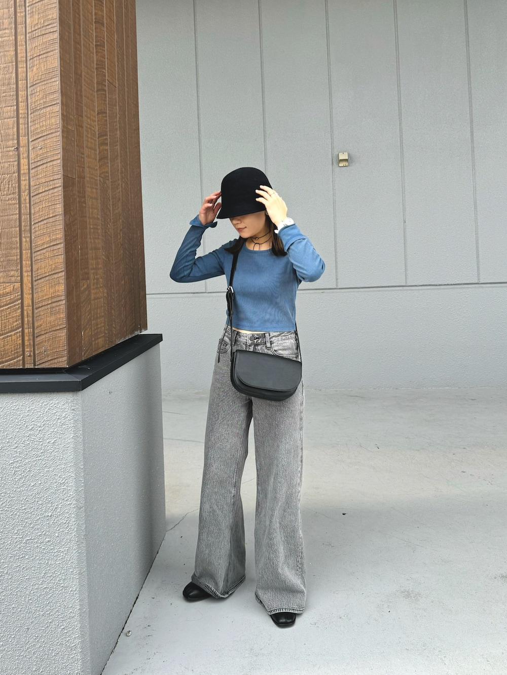ブルー系のトップス、グレー系のデニムパンツ、ブラック系のショルダーバッグを着用したレディースの秋コーディネートの2枚目の写真