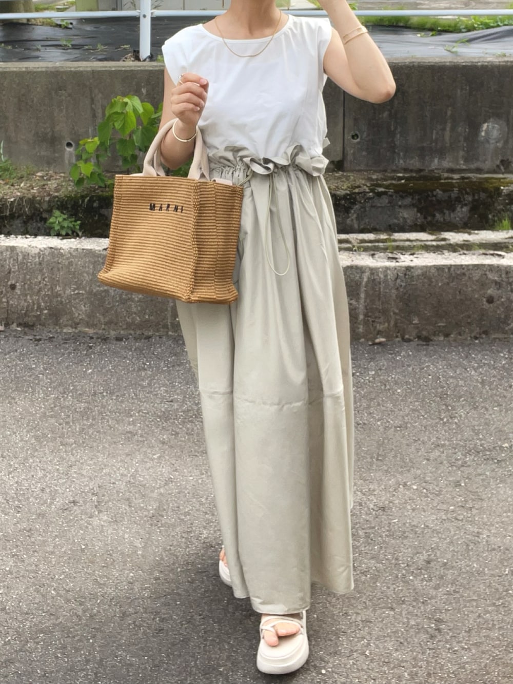 グリーン系のワンピース、ベージュ系のショルダーバッグ、ホワイト系のサンダルを着用したレディースの夏コーディネートの3枚目の写真