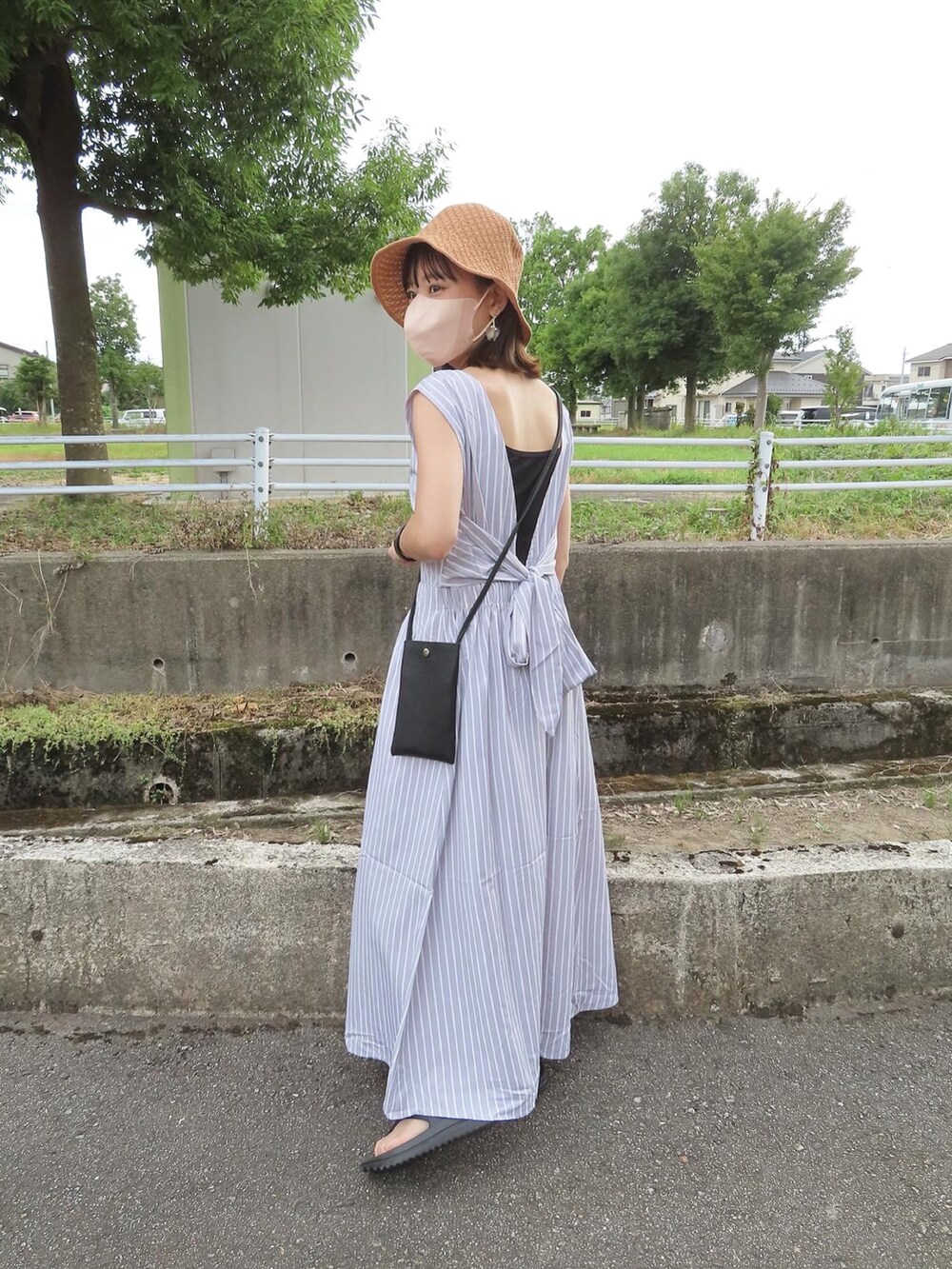 グレー系のワンピース、ブラック系のショルダーバッグ、ブラック系のサンダルを着用したレディースの夏コーディネートの2枚目の写真