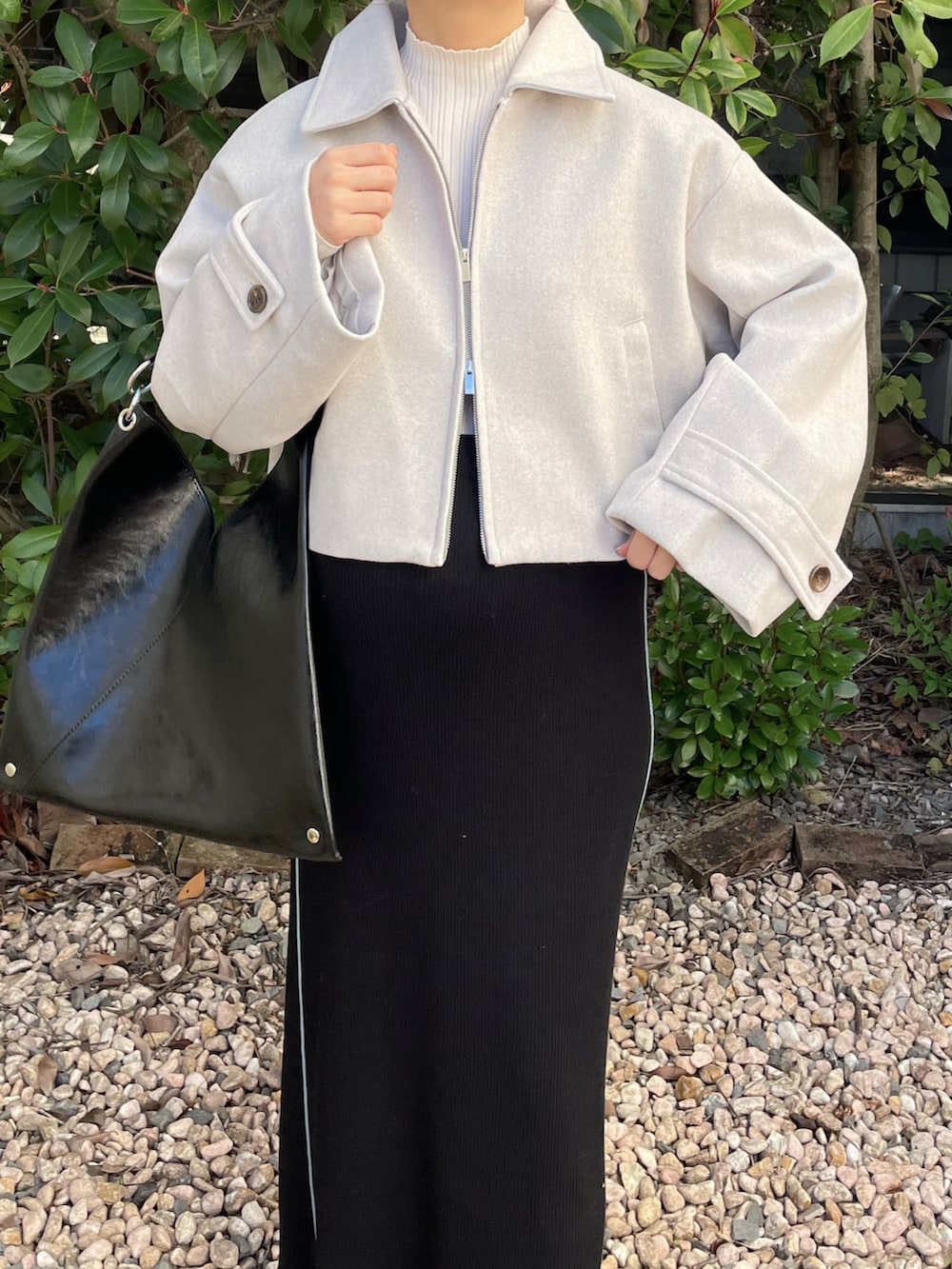 ホワイト系のブルゾン、ブラック系のバッグ、ホワイト系のスニーカーを着用したレディースの秋コーディネートの3枚目の写真