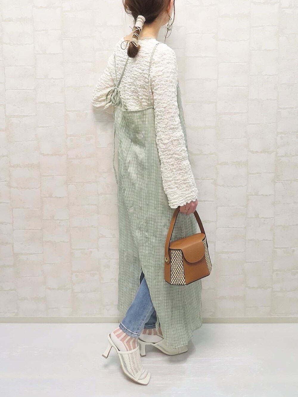 グリーン系のワンピース、ホワイト系のTシャツ/カットソー、ブルー系のデニムパンツを着用したレディースの春コーディネートの3枚目の写真