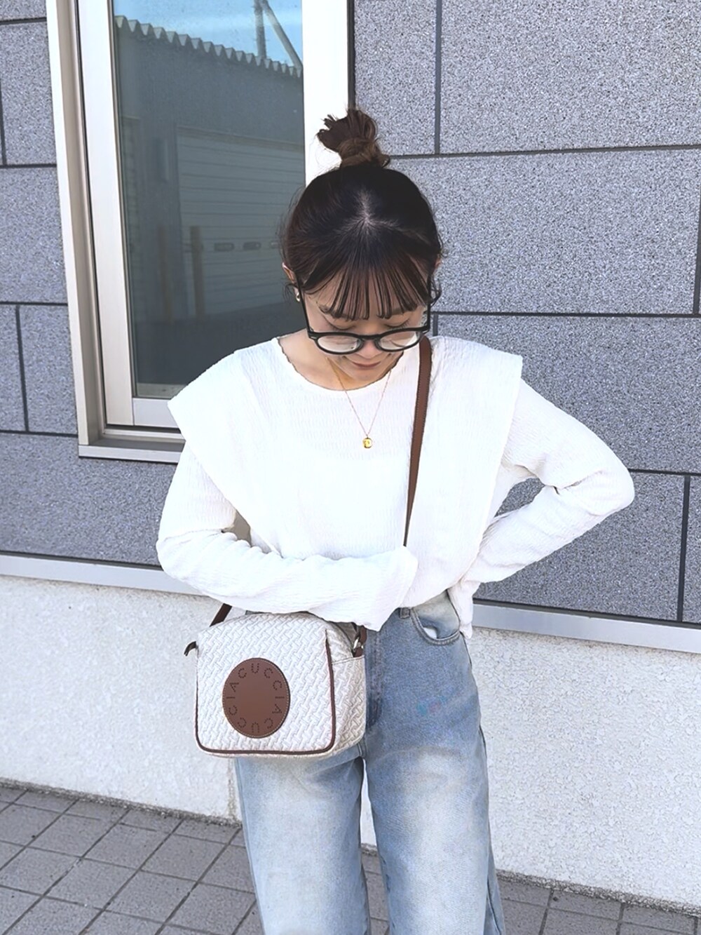 ホワイト系のTシャツ/カットソー、ブルー系のデニムパンツ、ホワイト系のショルダーバッグを着用したレディースの冬コーディネートの5枚目の写真