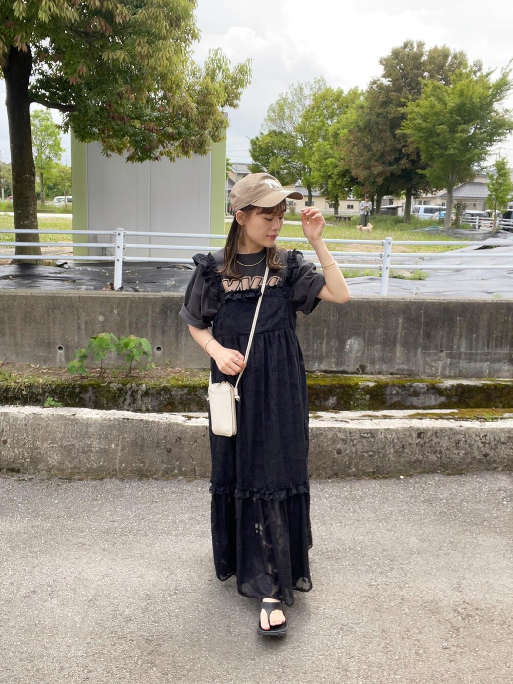 ブラック系のワンピース、ブラック系のTシャツ/カットソー、ブラック系のサンダルを着用したレディースの春コーディネートの2枚目の写真