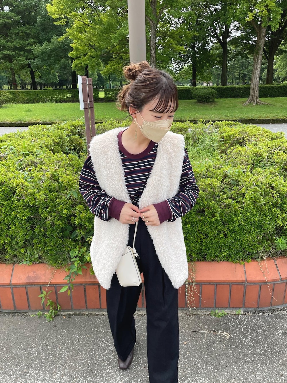 レッド系のトップス、ブラック系のパンツ、グレー系のベストを着用したレディースの秋コーディネートの3枚目の写真