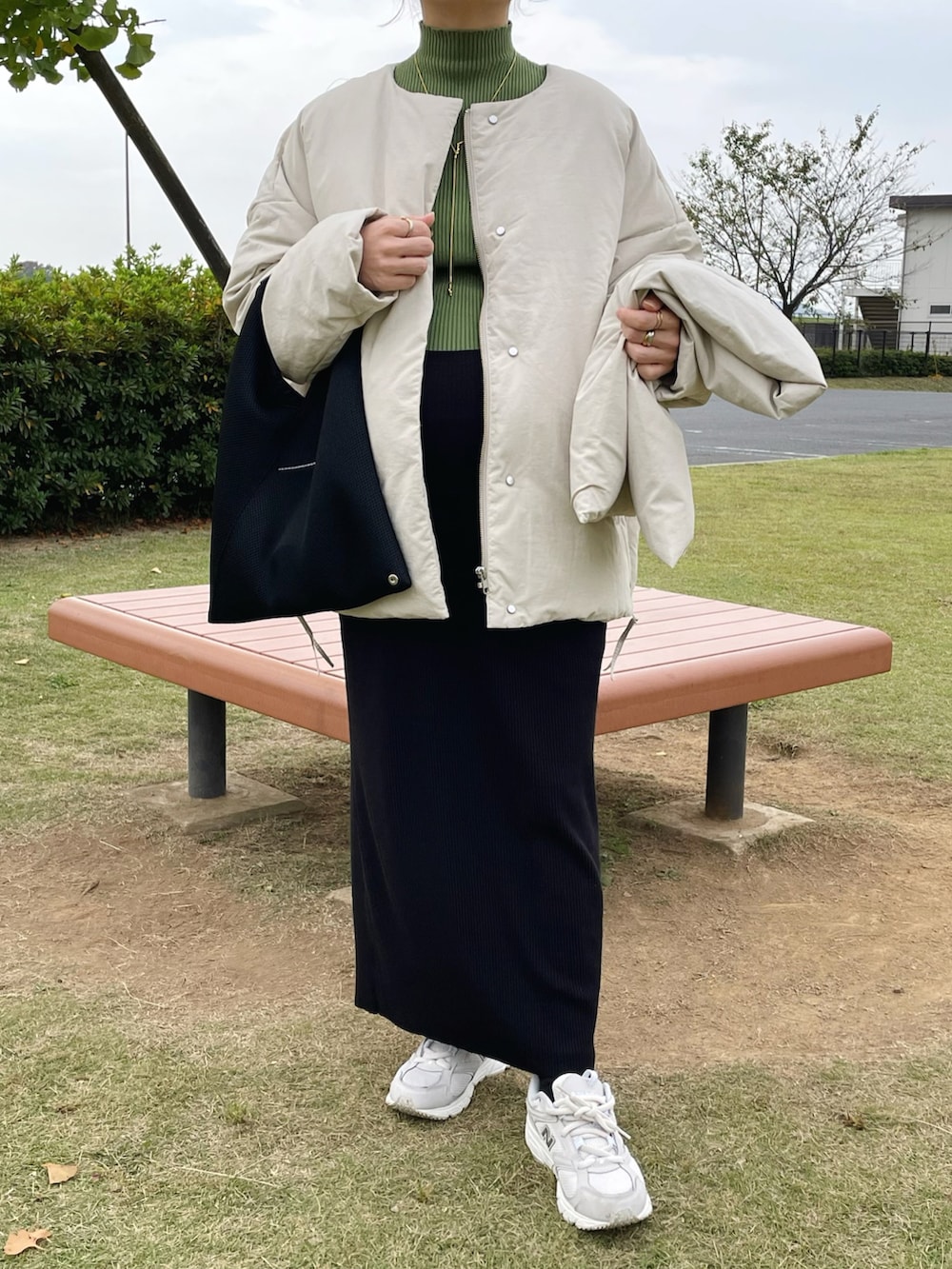 ブラック系のトートバッグ、ホワイト系のスニーカー、グリーン系のニット/セーターを着用したレディースの秋コーディネートの5枚目の写真