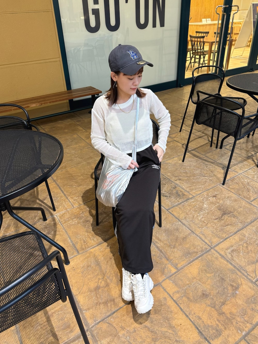 ホワイト系のトップス、ブラック系のスカート、シルバー系のトートバッグを着用したレディースの春コーディネートの2枚目の写真