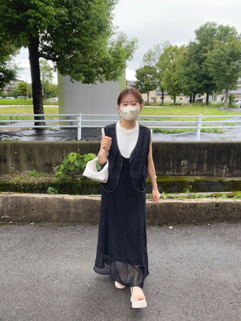 ブラック系のベスト、ホワイト系のニット/セーター、ブラック系のワンピースを着用したレディースの夏コーディネートの2枚目の写真