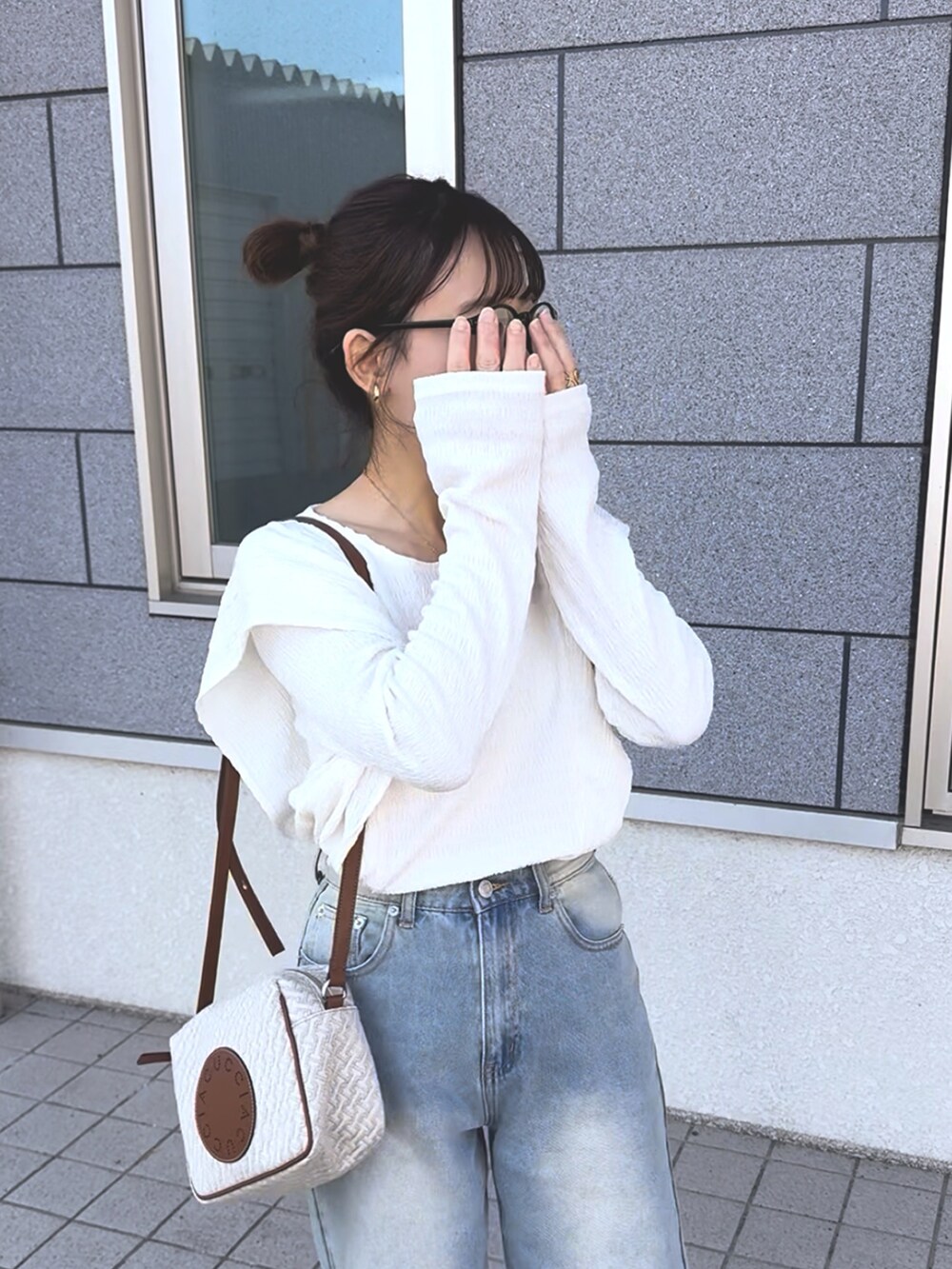 ホワイト系のTシャツ/カットソー、ブルー系のデニムパンツ、ホワイト系のショルダーバッグを着用したレディースの冬コーディネートの4枚目の写真