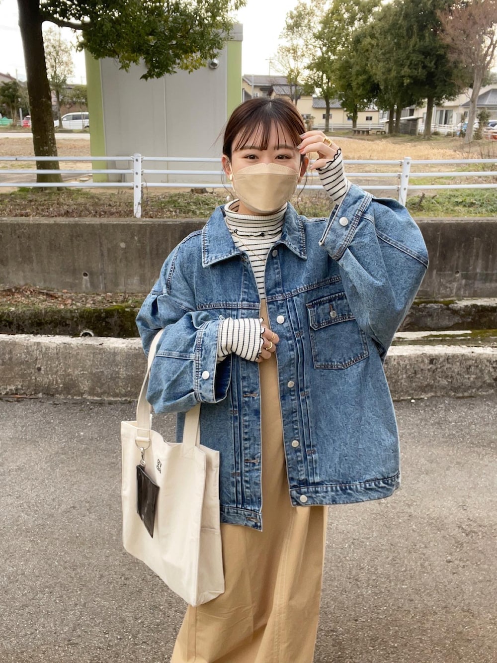 ベージュ系のワンピース、ホワイト系のトートバッグ、ブルー系のデニムジャケットを着用したレディースの春コーディネートの2枚目の写真