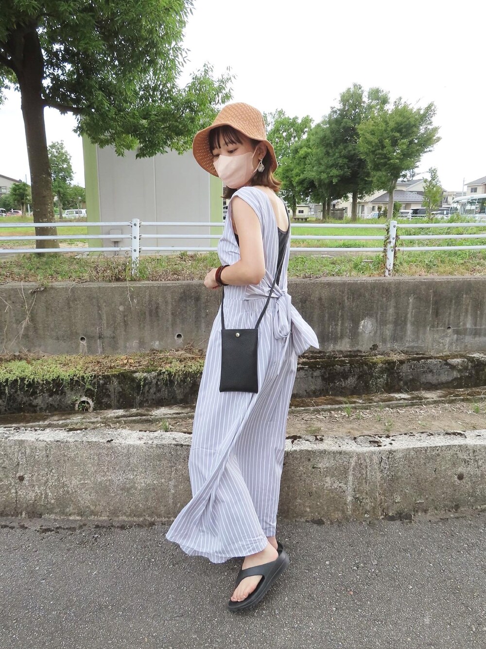 グレー系のワンピース、ブラック系のショルダーバッグ、ブラック系のサンダルを着用したレディースの夏コーディネートの4枚目の写真