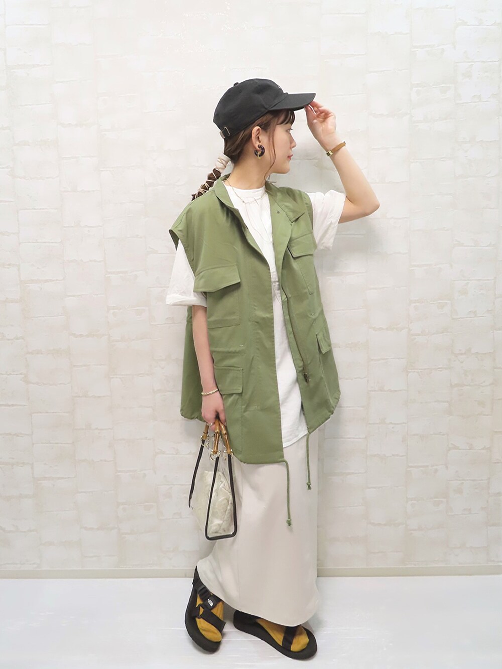 グリーン系のベスト、ホワイト系のシャツ/ブラウス、ホワイト系のスカートを着用したレディースの夏コーディネートの2枚目の写真