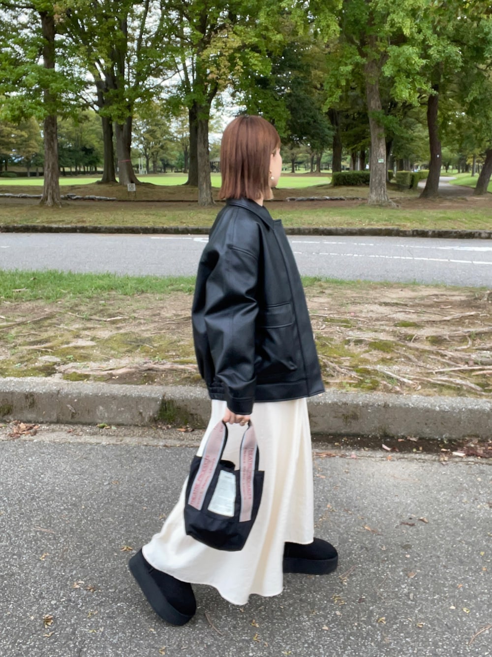 ブラック系のジャケット/アウター、ホワイト系のワンピース、ブラック系のショルダーバッグを着用したレディースの秋コーディネートの2枚目の写真