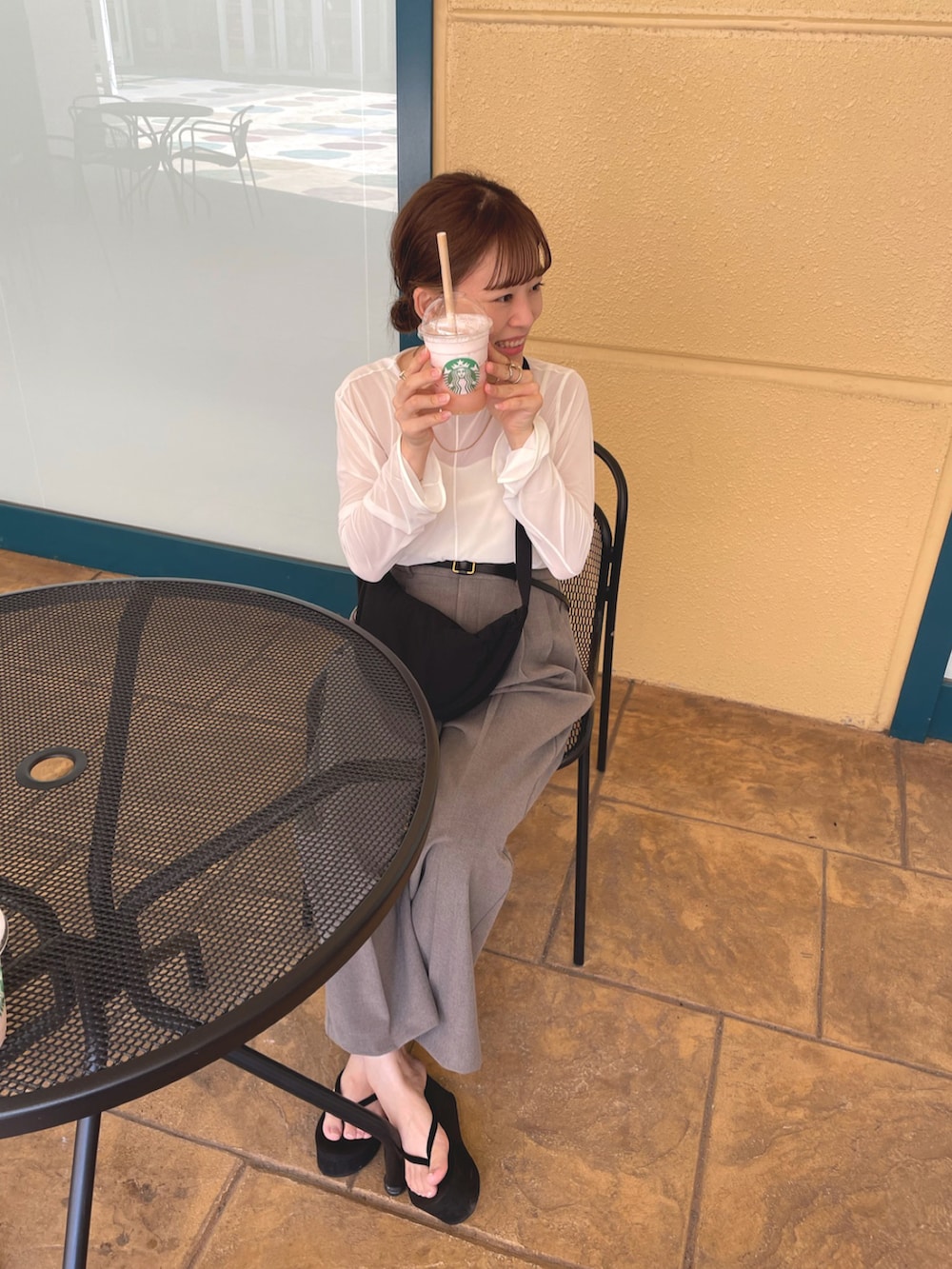 ホワイト系のトップス、ブラウン系のパンツ、ブラック系のショルダーバッグを着用したレディースの夏コーディネートの2枚目の写真