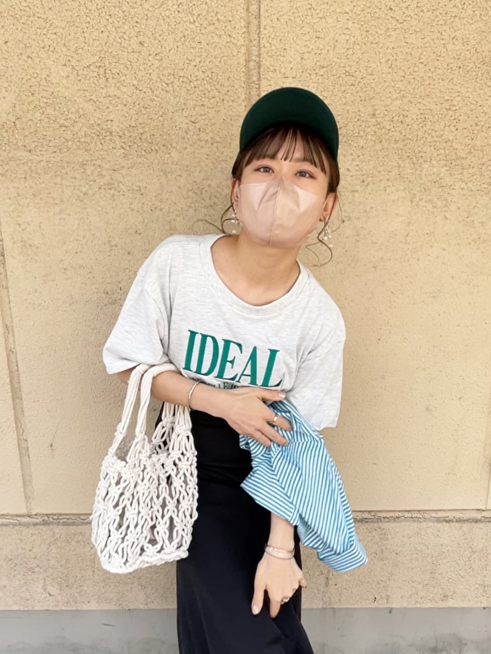 グリーン系のシャツ/ブラウス、ブラック系のスカート、ホワイト系のハンドバッグを着用したレディースの夏コーディネートの2枚目の写真