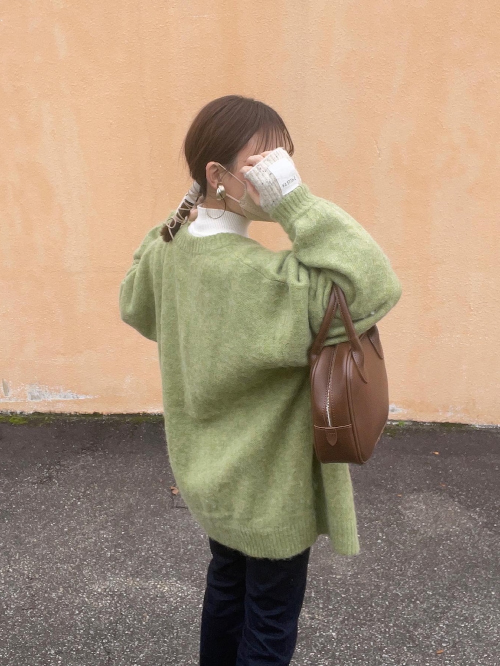 グリーン系のカーディガン/ボレロ、ホワイト系のニット/セーター、ブラウン系のショルダーバッグを着用したレディースの冬コーディネートの3枚目の写真