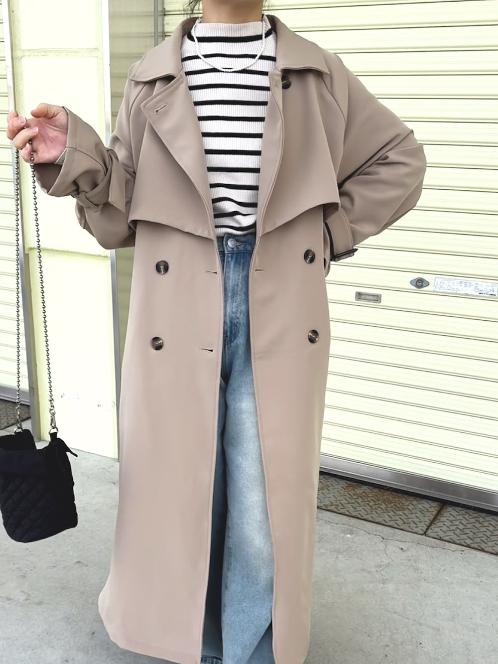 イエロー系のトレンチコート、グレー系のニット/セーター、ブルー系のデニムパンツを着用したレディースの冬コーディネートの4枚目の写真