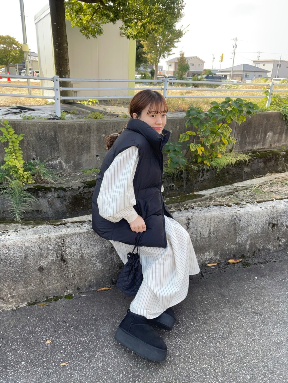 ブルー系のワンピース、ブラック系のベスト、ブラック系のブーツを着用したレディースの秋コーディネートの5枚目の写真