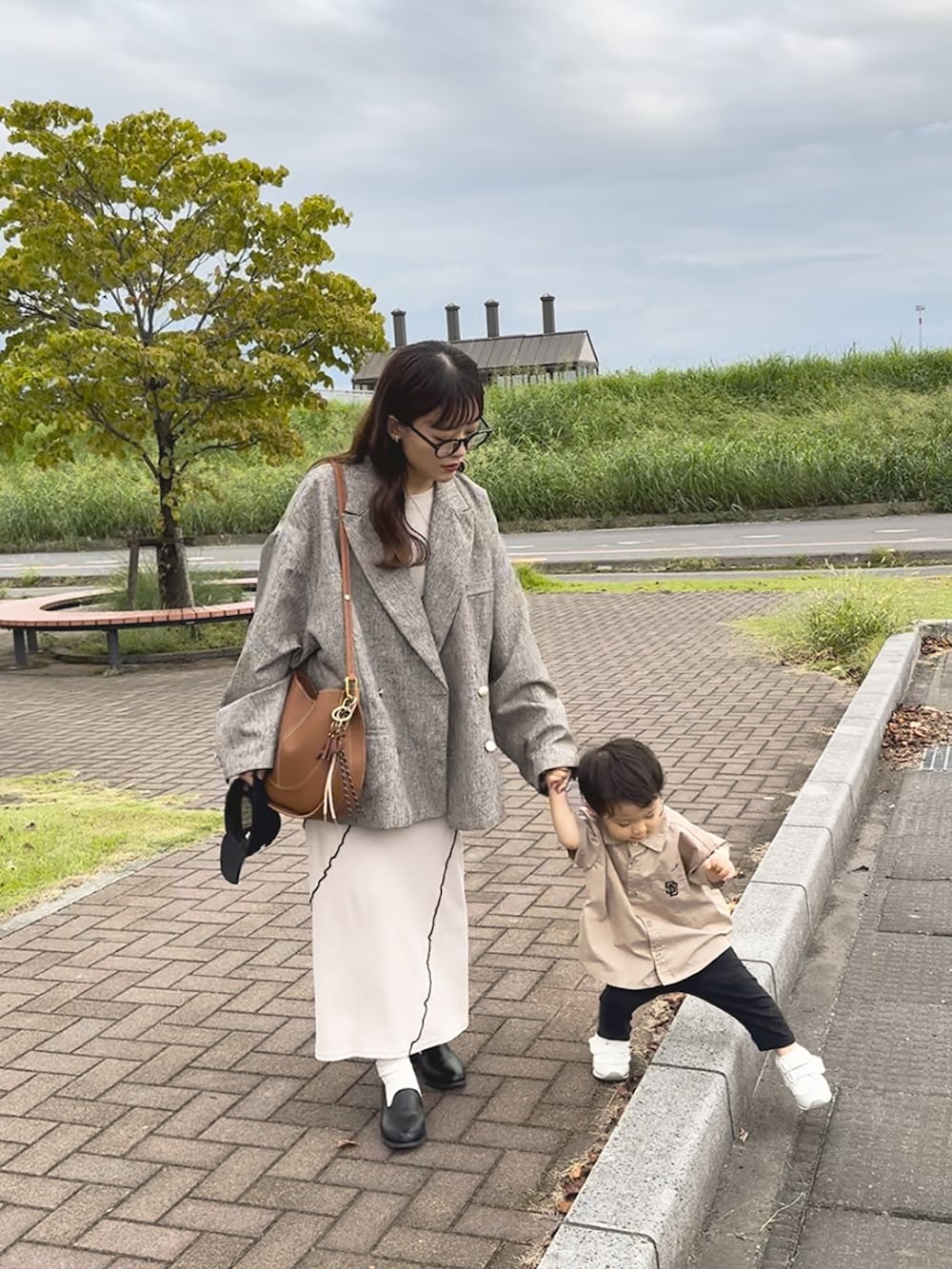 ベージュ系のテーラードジャケット、ベージュ系のワンピース、ブラウン系のショルダーバッグを着用したレディースの秋コーディネートの3枚目の写真