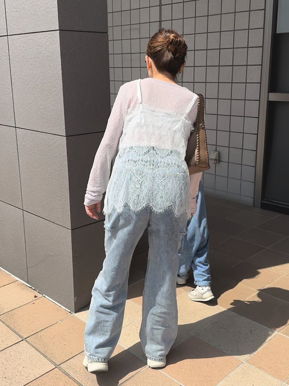 ホワイト系のキャミソール、ベージュ系のスニーカー、その他のデニムパンツを着用したレディースの春コーディネートの3枚目の写真