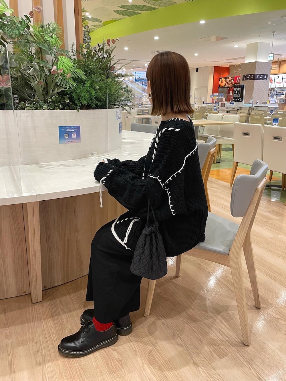 ブラック系のニット/セーター、ブラック系のショルダーバッグ、ブラック系のブーツを着用したレディースの秋コーディネートの2枚目の写真