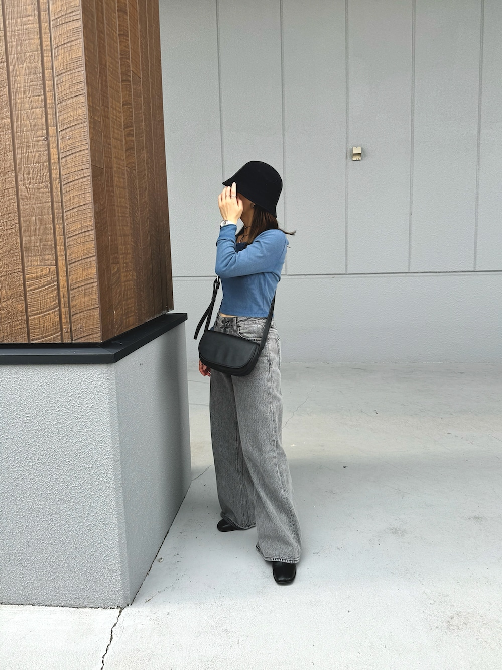 ブルー系のトップス、グレー系のデニムパンツ、ブラック系のショルダーバッグを着用したレディースの秋コーディネートの4枚目の写真