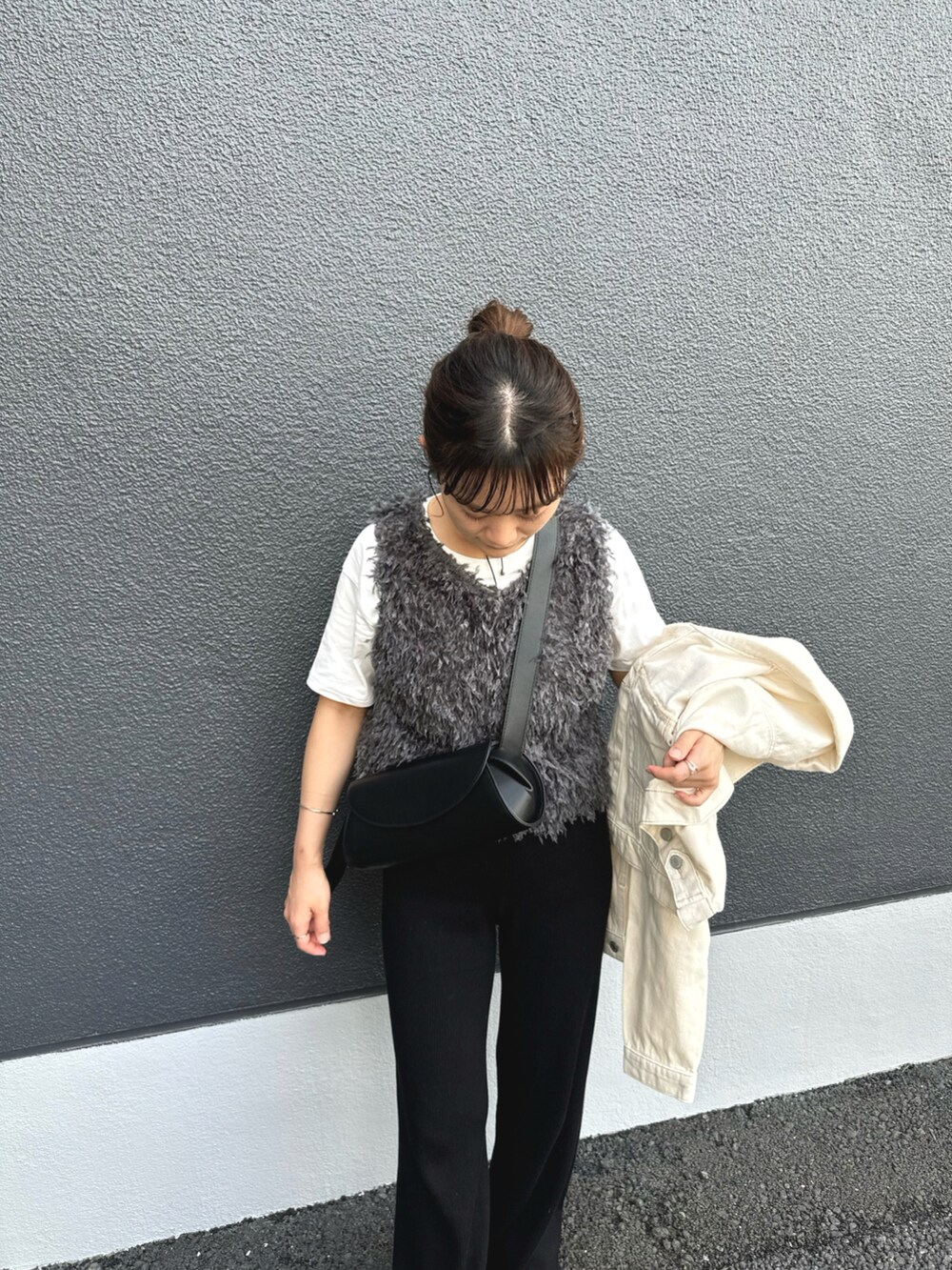 グレー系のベスト、ブラック系のパンツ、ホワイト系のデニムジャケットを着用したレディースの秋コーディネートの3枚目の写真
