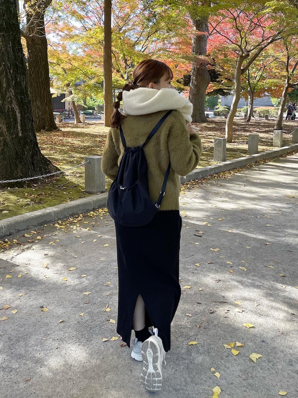 グリーン系のニット/セーター、ブラック系のバックパック/リュック、ホワイト系のスニーカーを着用したレディースの秋コーディネートの5枚目の写真