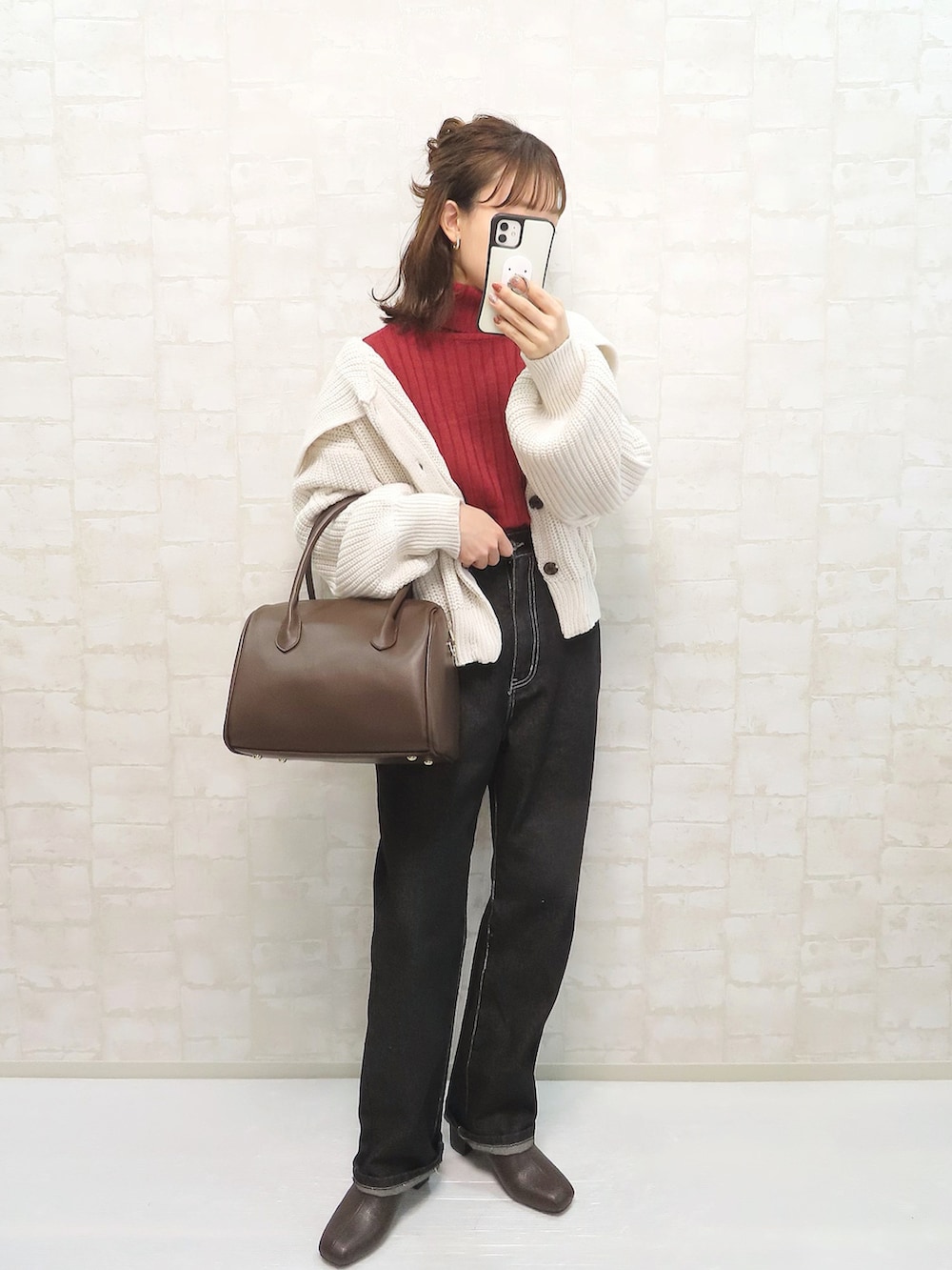 ホワイト系のカーディガン/ボレロ、レッド系のニット/セーター、ブラック系のデニムパンツを着用したレディースの冬コーディネートの2枚目の写真