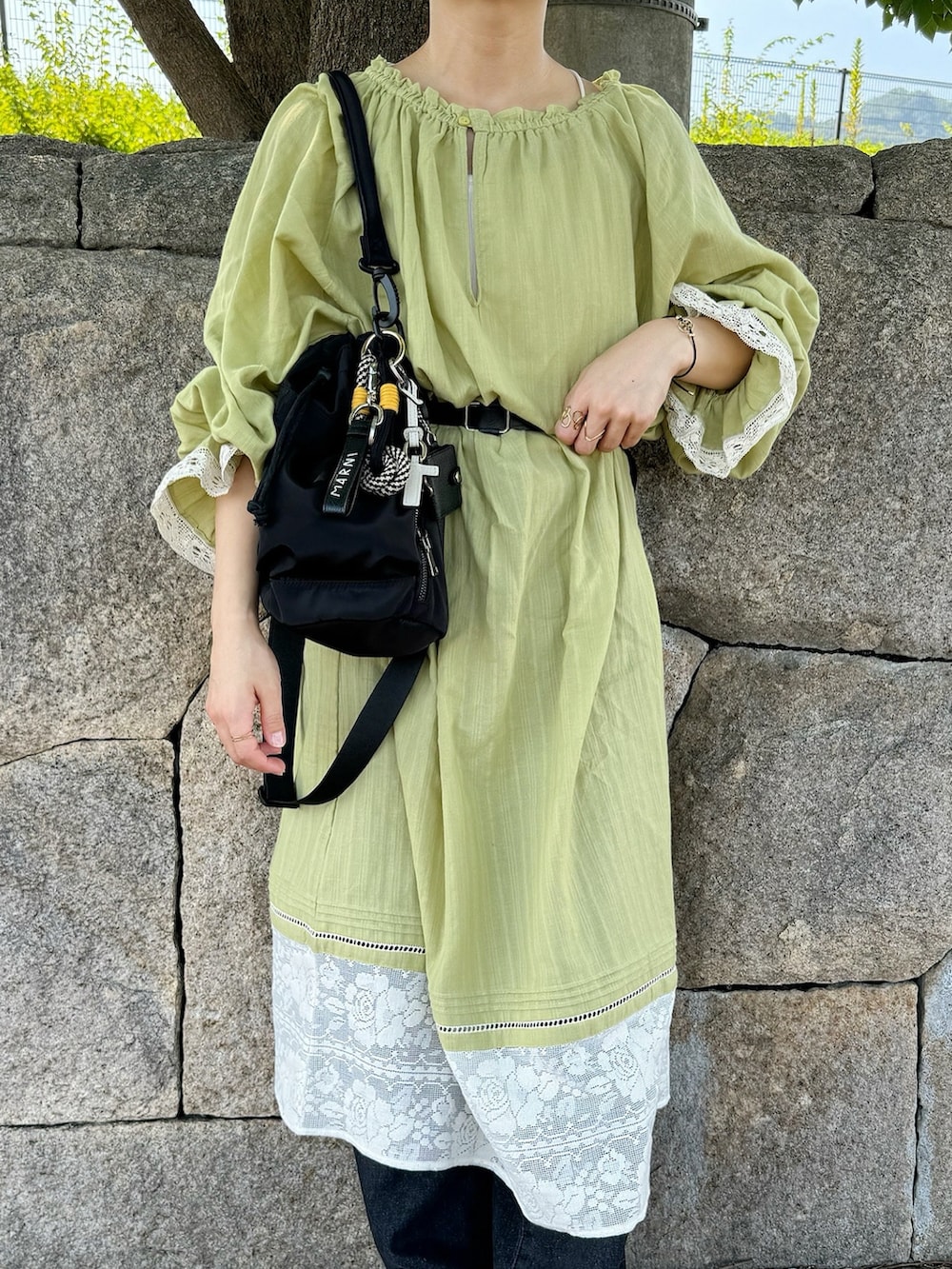 グリーン系のワンピース、ホワイト系のスニーカー、ブルー系のデニムパンツを着用したレディースの夏コーディネートの3枚目の写真