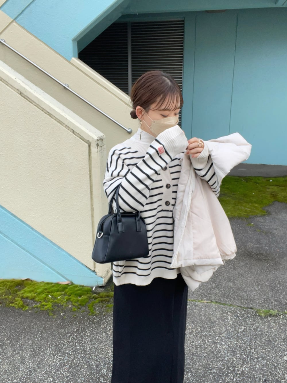 ホワイト系のニット/セーター、ホワイト系のダウンベスト、ブラック系のスカートを着用したレディースの冬コーディネートの2枚目の写真