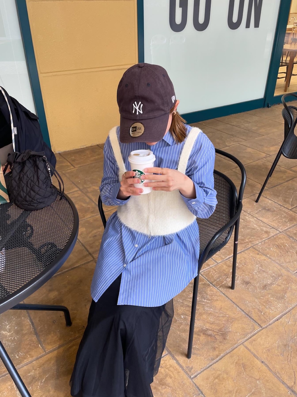 ブルー系のシャツ/ブラウス、ホワイト系のベスト、ブラック系のスカートを着用したレディースの春コーディネートの2枚目の写真