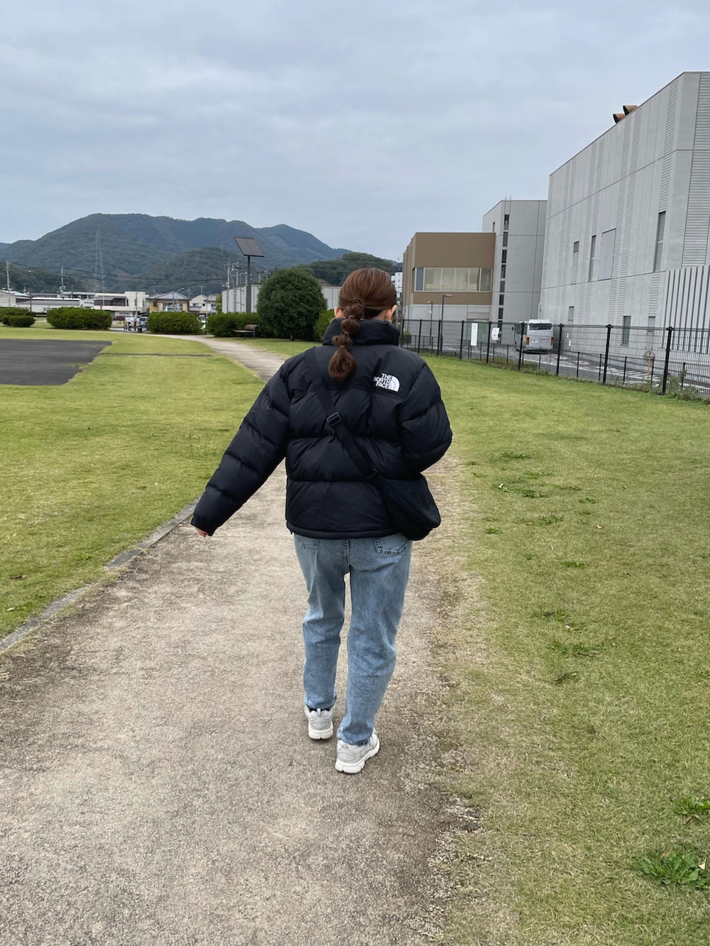 ブラック系のダウンジャケット/コート、ホワイト系のニット/セーター、ブルー系のデニムパンツを着用したレディースの冬コーディネートの3枚目の写真