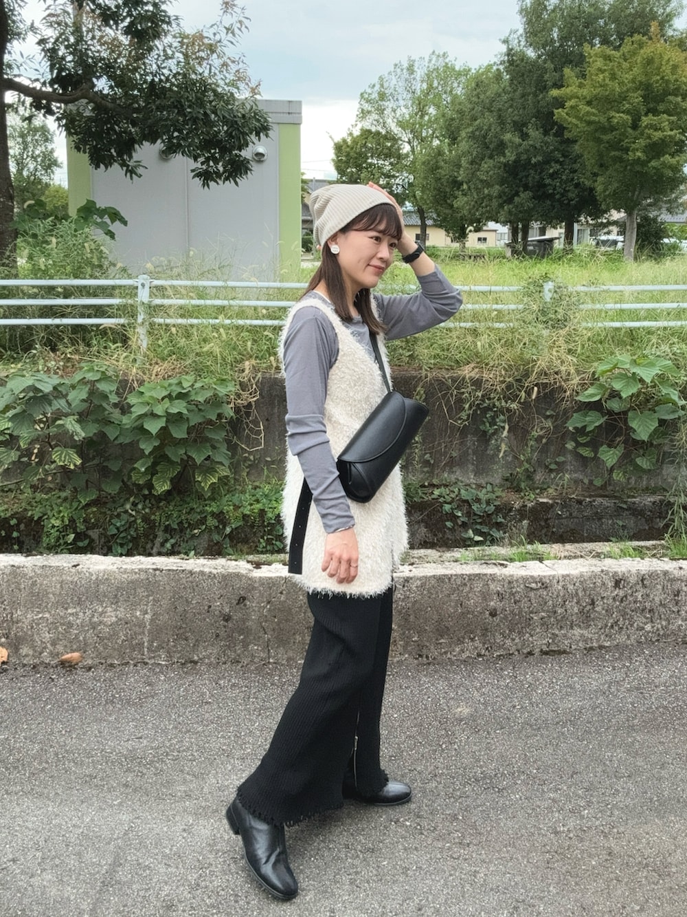 グレー系のTシャツ/カットソー、ホワイト系のベスト、ブラック系のスカートを着用したレディースの秋コーディネートの2枚目の写真